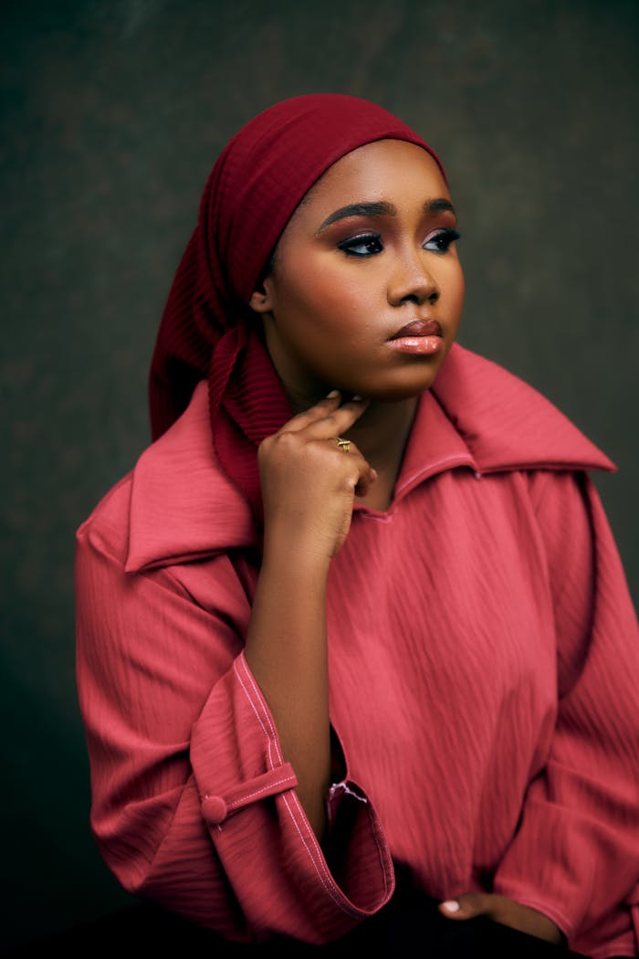 Home Young woman in a red outfit, deep in thought against a neutral background.